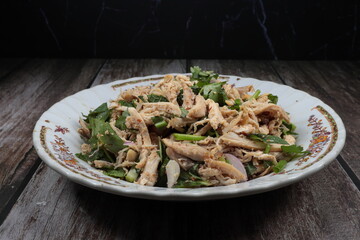 Thai spicy salad. Spicy roasted chicken salad mixed with fresh shallot, mint, basil and chilly serving on the plate. Famous Thai appetizer menu in Asian restaurant.