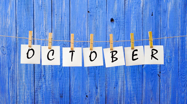 Month of October. The inscription of the word october on cards on a wooden blue background. Autumn, nature and bright colors. Calendar.	