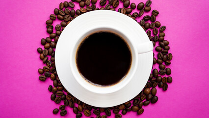 A cup of coffee with coffee beans on a bright pink background. Close-up of a coffee drink.	