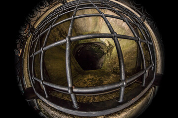 the interior of an old deep well secured with a massive steel grate, photographed with a fisheye lens