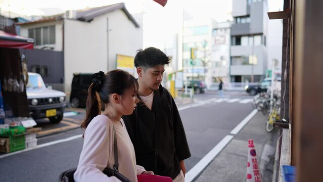愛知県名古屋市でたこ焼きを食べる２０代の若い日本人カップル  A young Japanese couple in their 20s eating takoyaki in Nagoya City, Aichi Prefecture