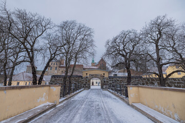 Panoramic view of gates and bridge at the Akershus castle in central Oslo on a cold winter day. Visible Barracks, church and towers in the background. and trees with bridge in the foreground