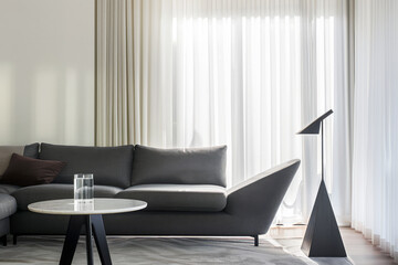 Elegant living room interior with a sofa, a lamp and a table close to a window for natural light