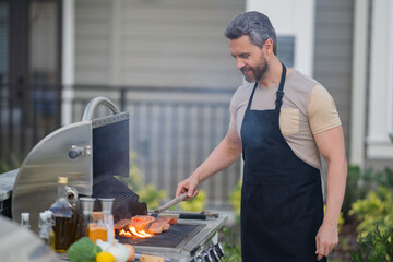 Hispanic man cooking on barbecue in the backyard. Chef preparing barbecue. Barbecue chef master. Handsome man preparing barbecue, bbq meat. Grill and barbeque. - Powered by Adobe
