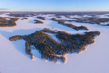 Aerial view over snow covered winter landscape with frozen lakes and boreal forest in northeast...