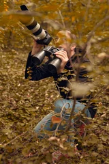 Tuinposter Man using binoculars and camera for birdwatching and other observing animals in nature. © astrosystem