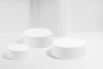 Abstract scene with three white round podiums with striped pillar as decoration, mockup on white background. Template for presentation cosmetic products, gifts, advertising, design in fashion style.