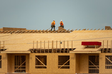 Roofing on roof. Builder roofer install new roof. Construction worker roofing on a large roof apartment building development. Roofer carpenter working on roof structure construction site. - obrazy, fototapety, plakaty