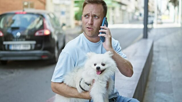 Handsome young caucasian man relaxes on urban street bench, engrossed in serious talk on his smartphone, with his faithful dog sitting by his side