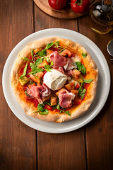 Pizza fatta in casa con prosciutto crudo, mozzarella di bufala, sugo e rucola, cibo italiano 
