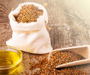Sesame seeds in sack and bottle of oil on wooden rustic table on sunlight