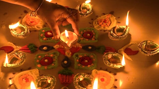 Clay diya lamps lit with rangoli during diwali celebration.