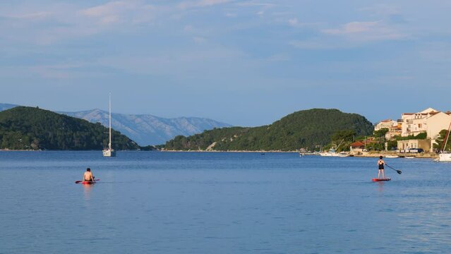 People paddling their boards on a bay in the Adriatic sea on a beautiful summer day. Holidays and travel destinations. 