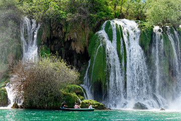Kravica Waterfall in Bosnia and Herzegovina. People enjoying themselves on the boats next to the...