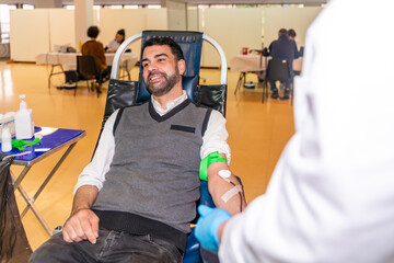 Man smiling sitting on chair in a blood donation pavilion - obrazy, fototapety, plakaty