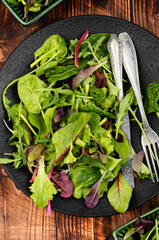 Salad from green leaves on wooden table.