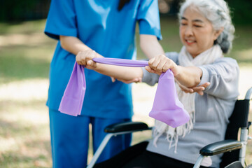 Asian physiotherapist helping elderly woman patient stretching arm during exercise correct with...