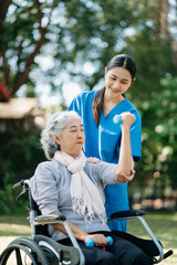 Asian physiotherapist helping elderly woman patient stretching arm during exercise correct with...