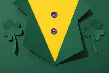 Clover leaves and paper suit on green background, top view