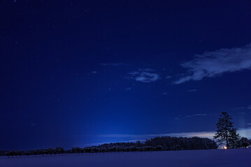 雪に覆われた大地と星が煌めく広大な夜の空の北海道の田舎の冬