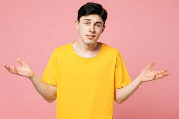 Young sad Caucasian man he wears yellow t-shirt casual clothes spread hands shrugging shoulders...