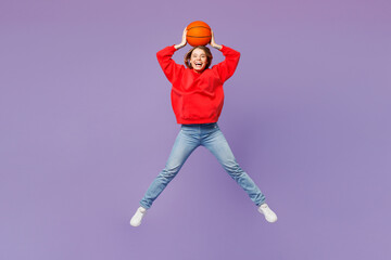 Full body young happy woman fan wear red hoody cheer up support basketball sport team hold in hand ball jump high look camera isolated on plain purple color background studio. Sport leisure concept.