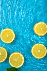 Fresh round orange slices floating in a pool with a rippled saturated blue water. Minimal tropical...