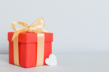 gift box with red bow and red heart on colored background. Perspective view. Flat lay