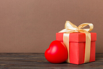 gift box with red bow and red heart on colored background. Perspective view. Flat lay