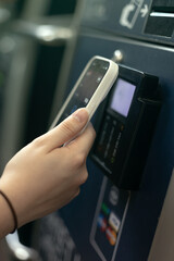 Woman using smart phone pay to buy the train ticket with self service machine in the station. selfservice machine with contactless phone payment.