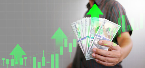 Economy growth concept. Cash in a man's hand with upward arrow and rising graph. Dollar grows...