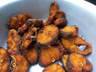 Dry tarmerik salt masala fish fry is a simple tasty delicious and flavourful fish fry in Aluminum pot,Hot Fried Fish on a Almuniyam container with Hot Oil,Hot bubbly and so delicious Fish,brown Fish 