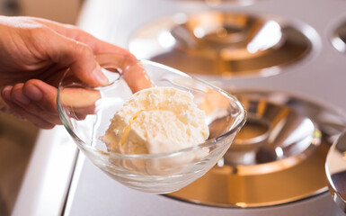 Scoop of creamy ice cream in spoon from the refrigerator container