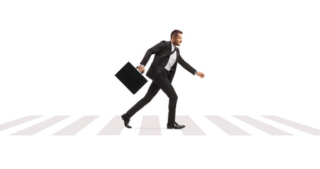 Full length profile shot of a businessman with a briefcase running over a pedestrian zebra crossing