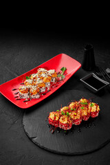 Obraz na płótnie Canvas Gourmet sushi rolls on red and black dishware