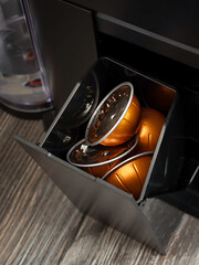 Close-up of an open container for used coffee capsules in a coffee machine.