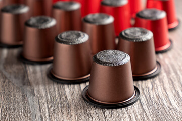 Close-up of many multi-colored capsules for a coffee machine lie on a beautiful wooden table.