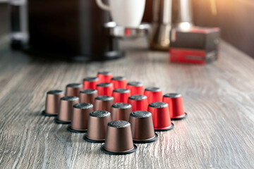 There are many colorful capsules for the coffee machine on a beautiful wooden table.
