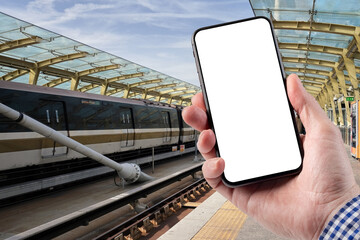 A man holds a smartphone in his hand. The city metro train is arriving outdoor the station.
