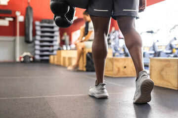 Fit African American man training at a gym, holding boxing gloves, with copy space
