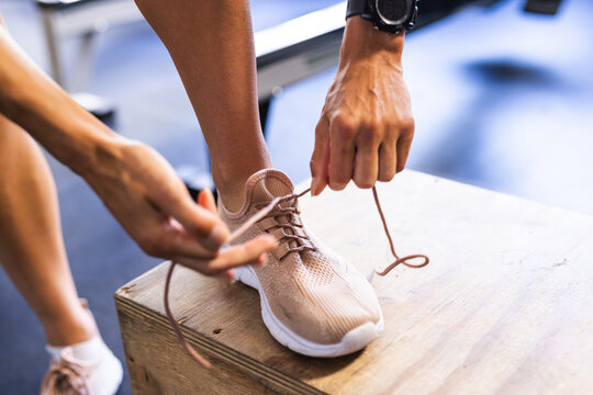 Close-up of a fit person tying their running shoe in a gym setting