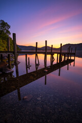 Wooden jetty reflections at sunrise in lake at Derwentwater in The Lake District, UK. - 736989975