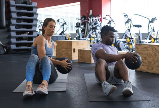 Fit diverse couple exercising at the gym, focused on strengthening their core muscles together