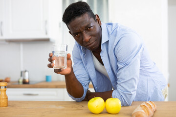 Man holding glass, drinking water at home