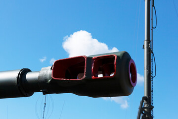 Muzzle barrel of military tank artillery gun on a blue sky background. copy space, selective focus,...