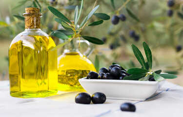 still life of olives and oil on a table against a background of olive trees