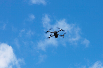Modern quadcopter flies against the blue sky. Copy space.