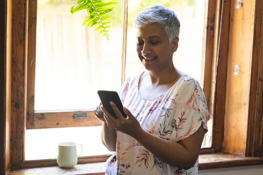 A mature biracial woman using a smartphone at home