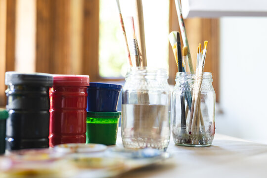 A variety of paintbrushes rest in a jar on an artist's table