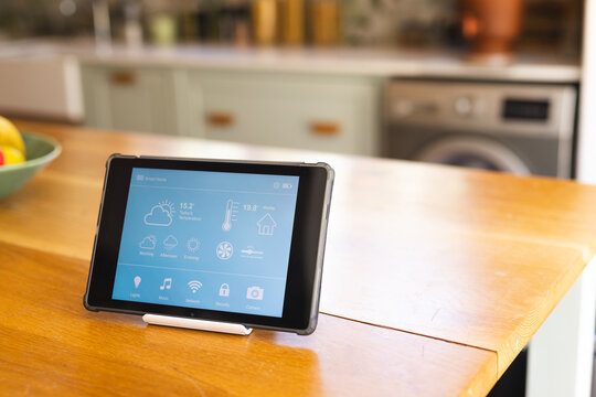 A tablet displays a smart home interface in a modern kitchen